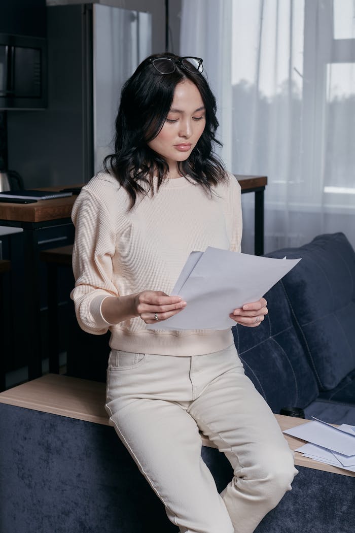 services-04 Focused young woman analyzing financial papers in a modern home setting.