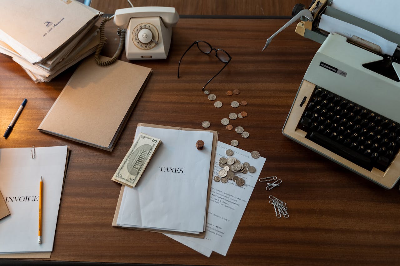 who-we-are Vintage workspace with typewriter, documents, and telephone on a wooden desk, evoking a classic office setting.