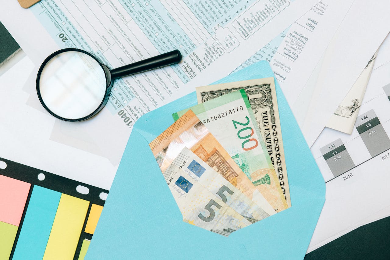about-us Close-up of tax documents and mixed currency in a blue envelope with a magnifying glass, perfect for financial analysis concepts.